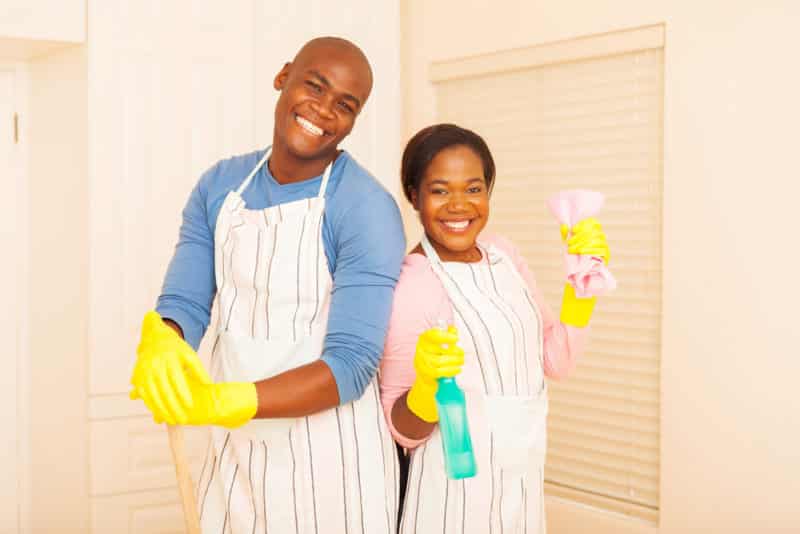 A man and woman holding cleaning supplies in their hands.