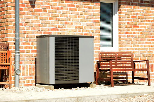 A small air conditioner sitting outside of a brick building.