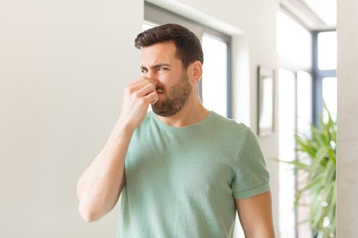 A man in green shirt holding his nose.