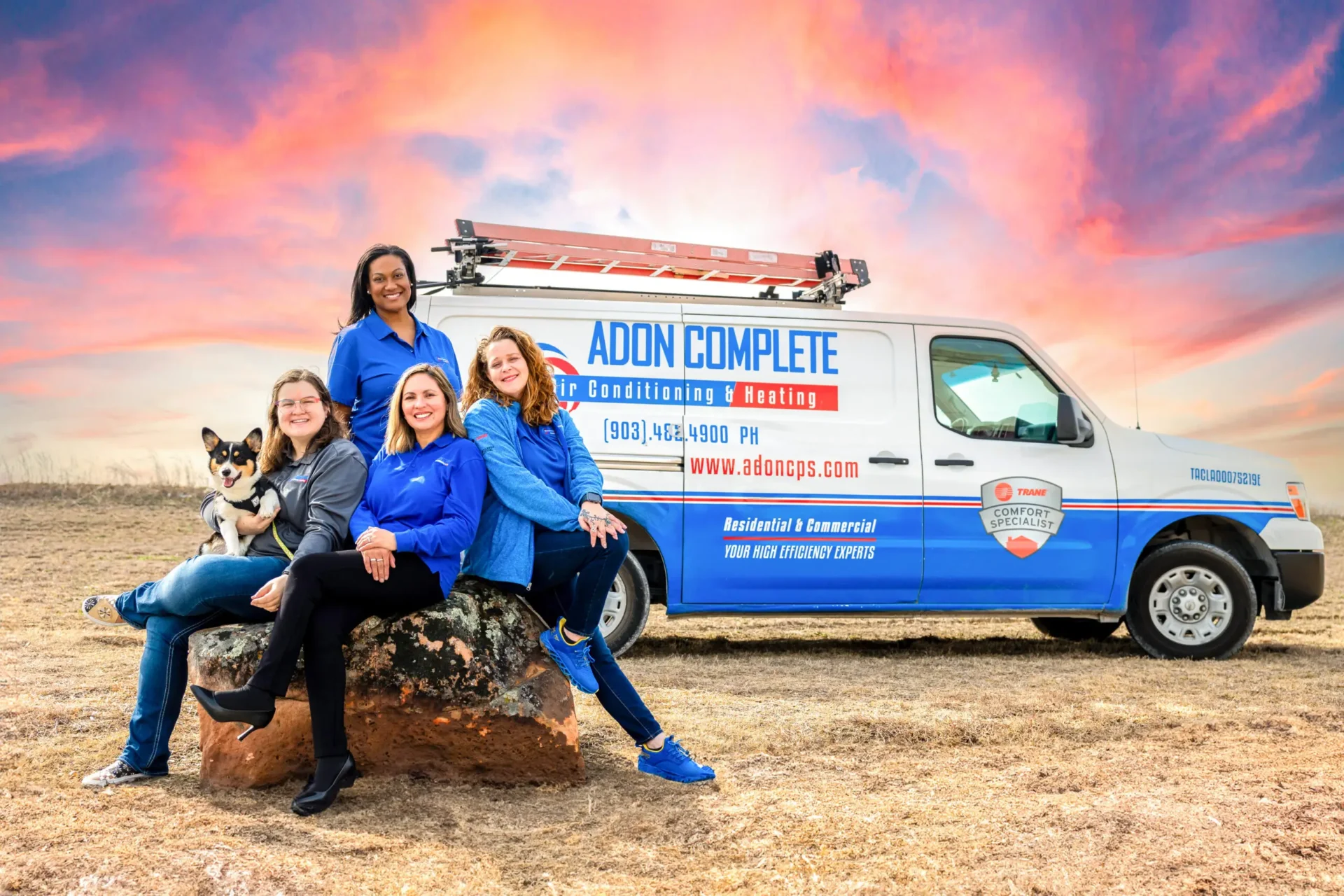 Four women and a dog in front of a van.