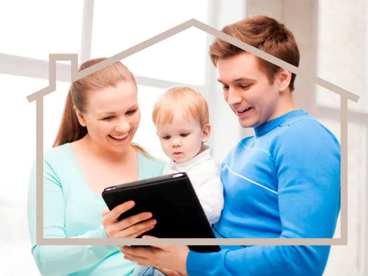A man and woman holding a baby looking at an ipad.